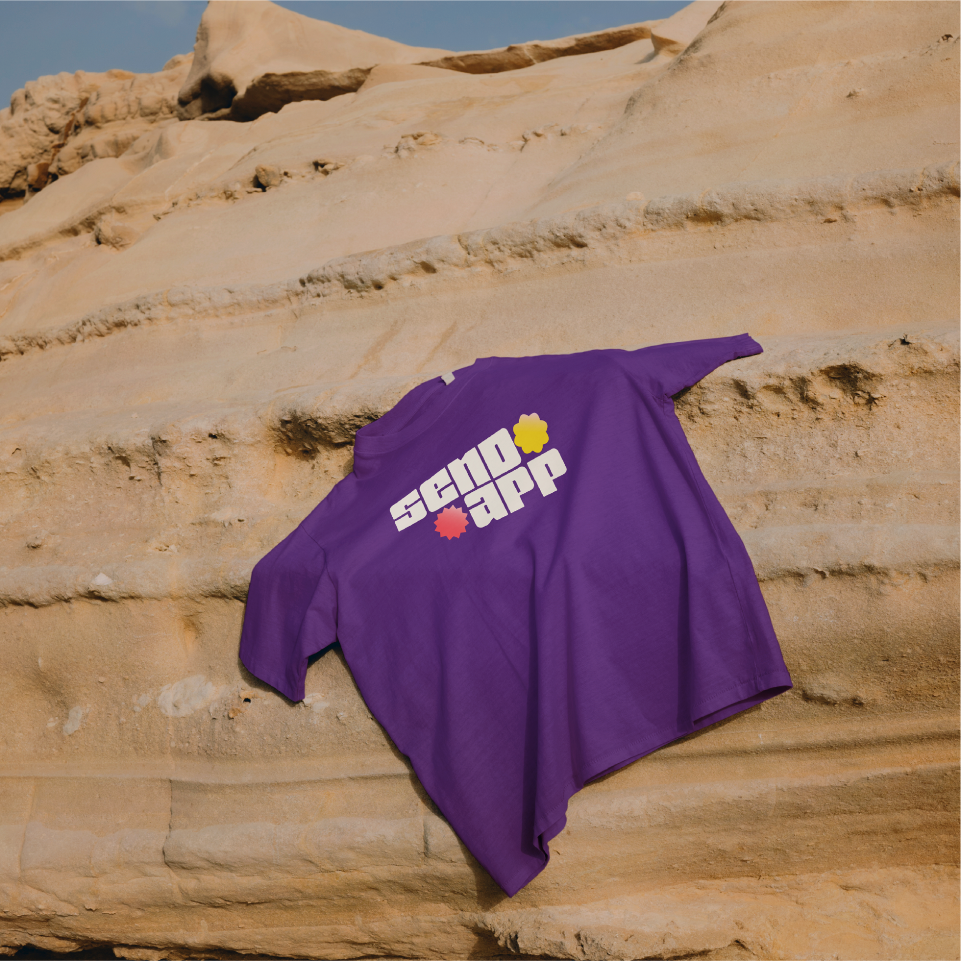 Send App brand identity - purple t-shirt mockup with logo placed on desert rock formation