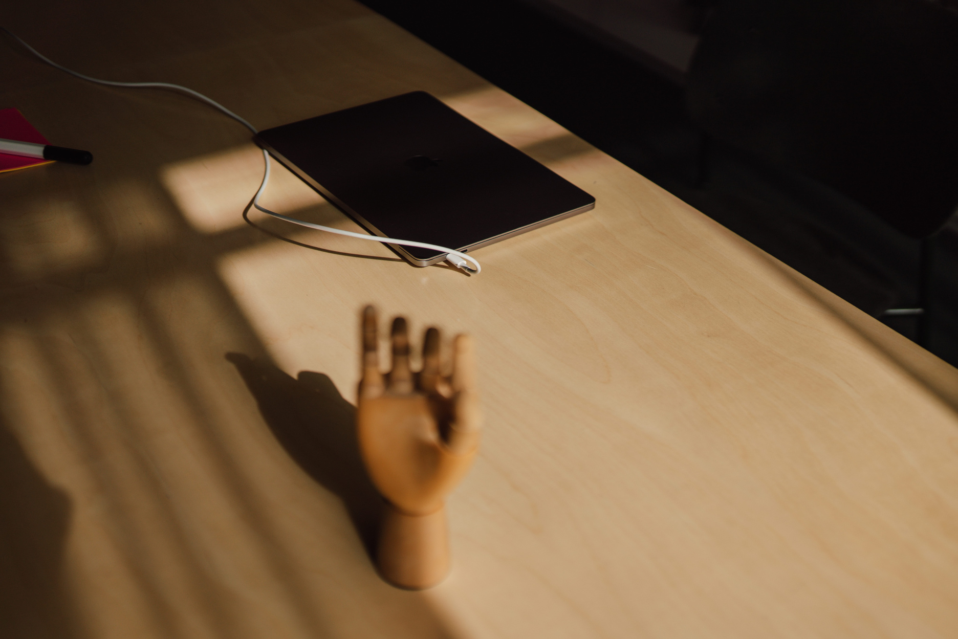 Wooden mannequin hand and closed laptop on a sunlit desk in the Verve office