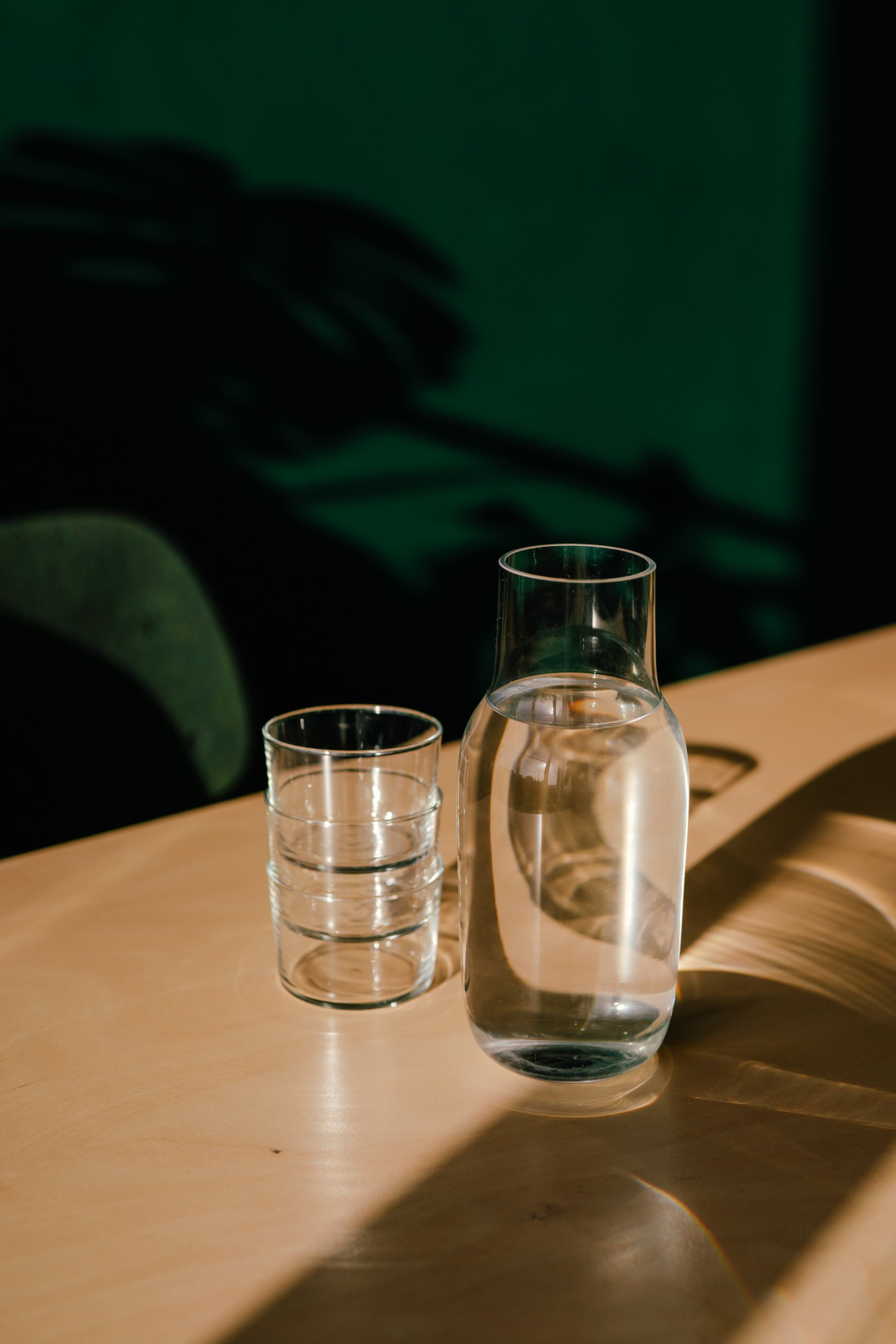 Water carafe and stacked glasses on a sunlit wooden desk in the Verve office