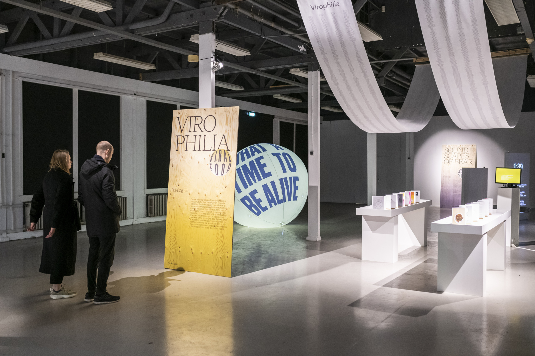 Visitors at Dutch Design Week viewing the Virophilia exhibition installation with signage and displays