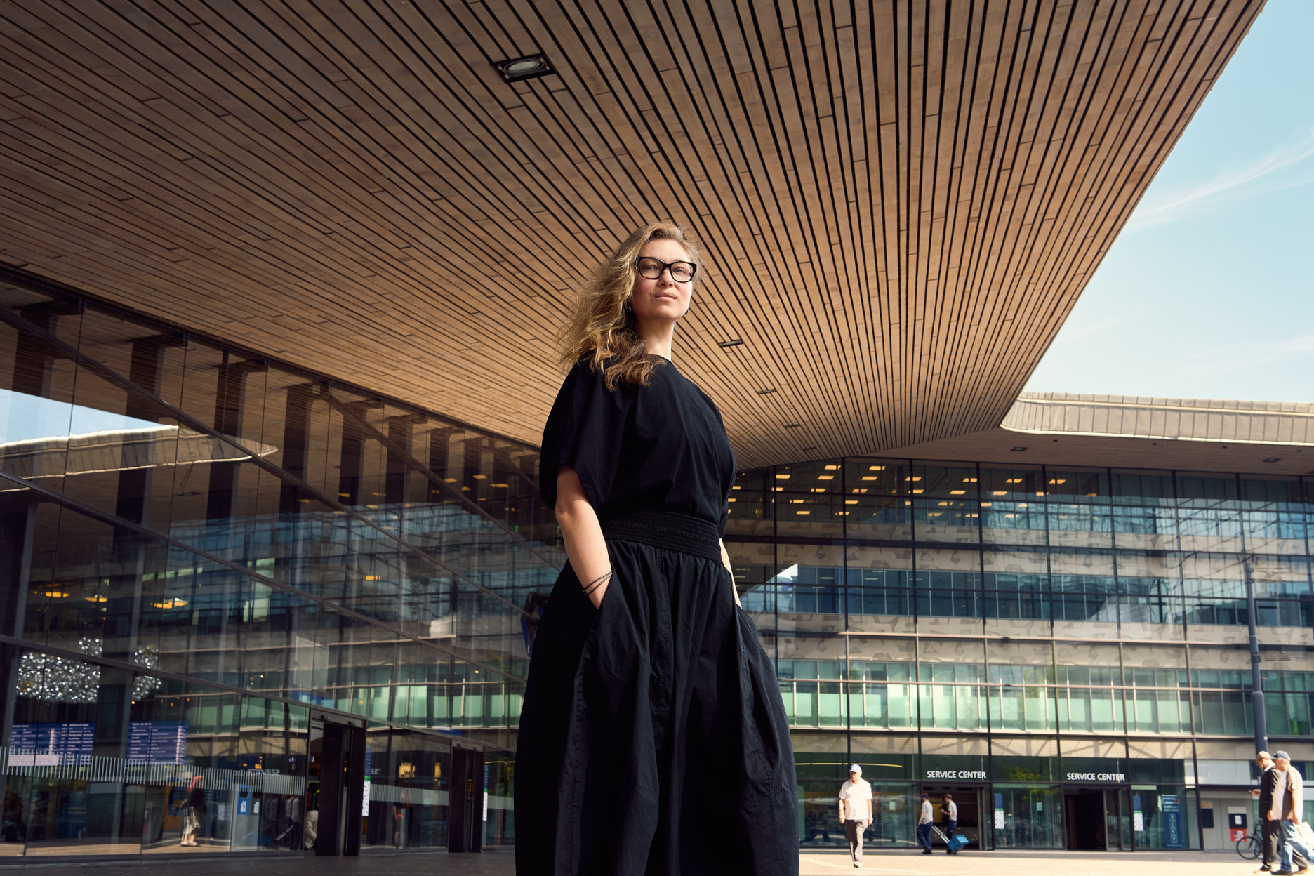 Angelina Severino, Lebara's Global Design & UX Lead, standing in front of a modern glass building with a sweeping wood-slatted ceiling.
