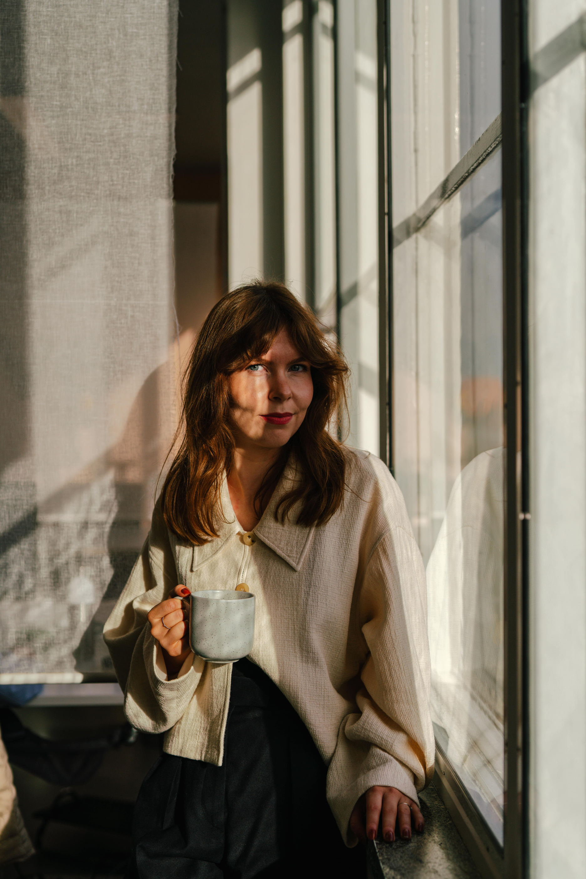 Sarah de Jager, Digital Design Lead at Verve, looking out a sunlit window with a coffee mug